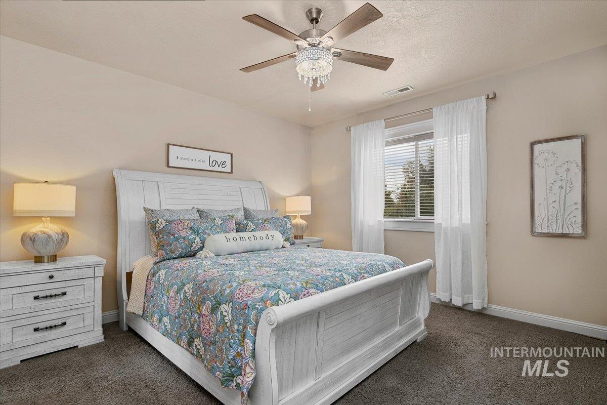 Bedroom featuring dark colored carpet, ceiling fan, and a textured ceiling