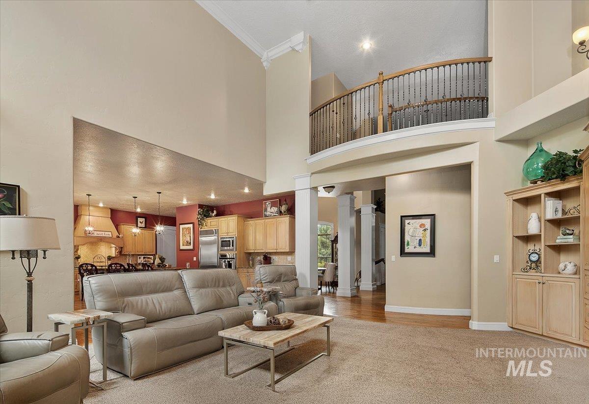 Living area featuring light wood-style floors, a high ceiling, and crown molding