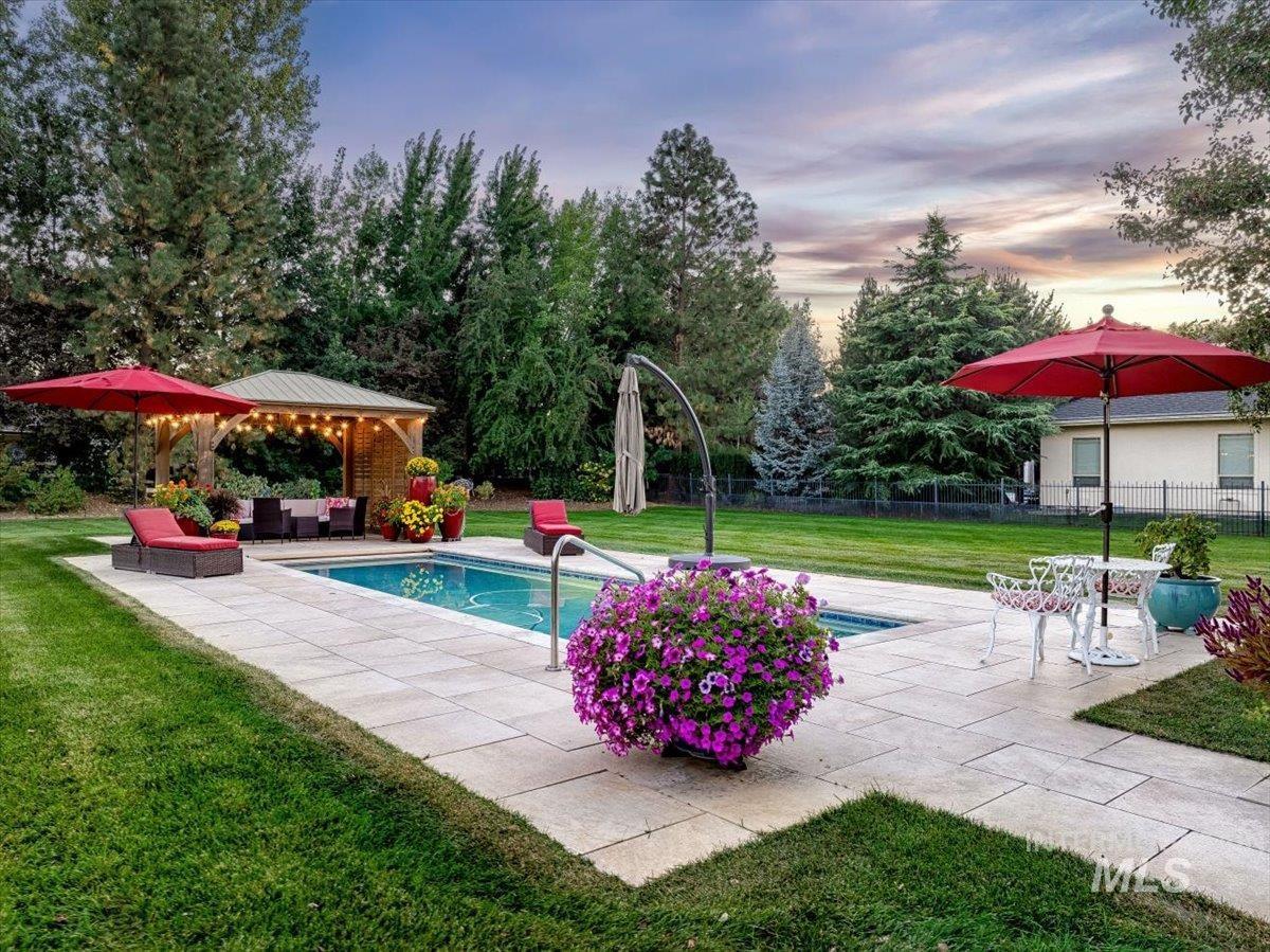 Pool at dusk featuring an outdoor hangout area, a patio area, a gazebo, and view of scattered trees