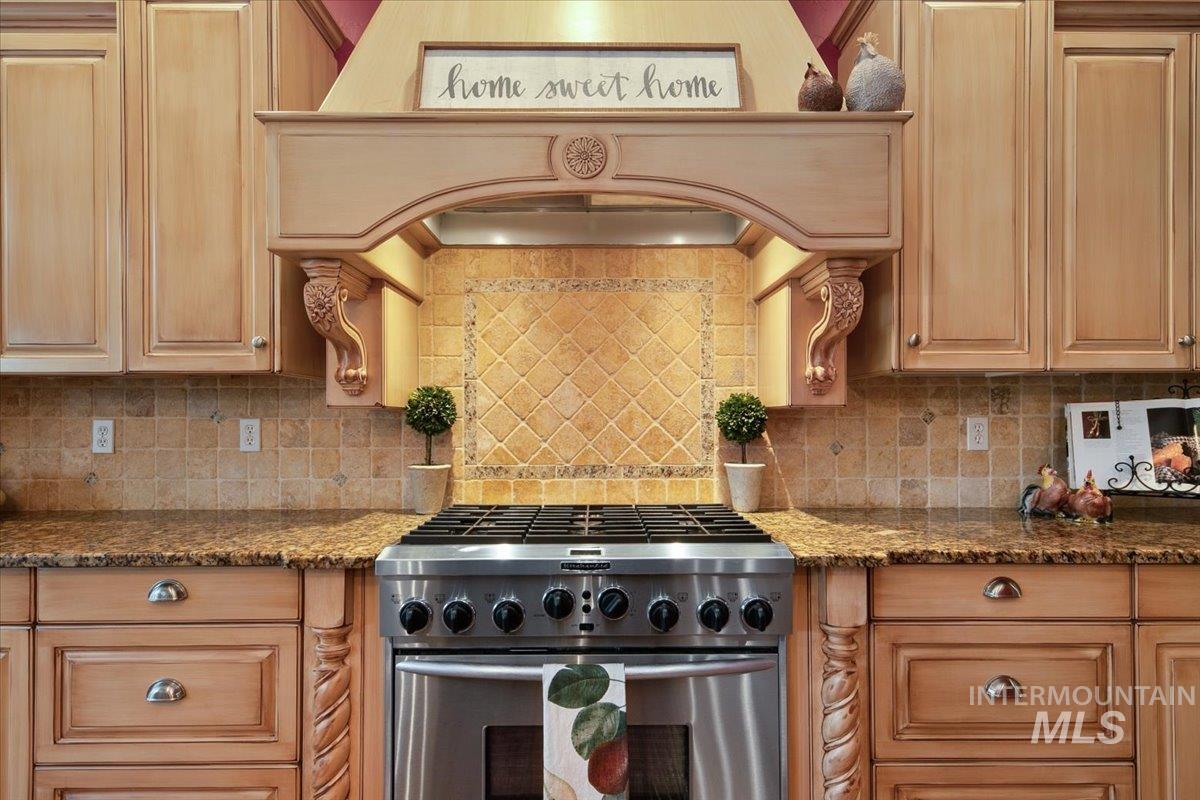 Kitchen featuring gas range, dark stone counters, and backsplash
