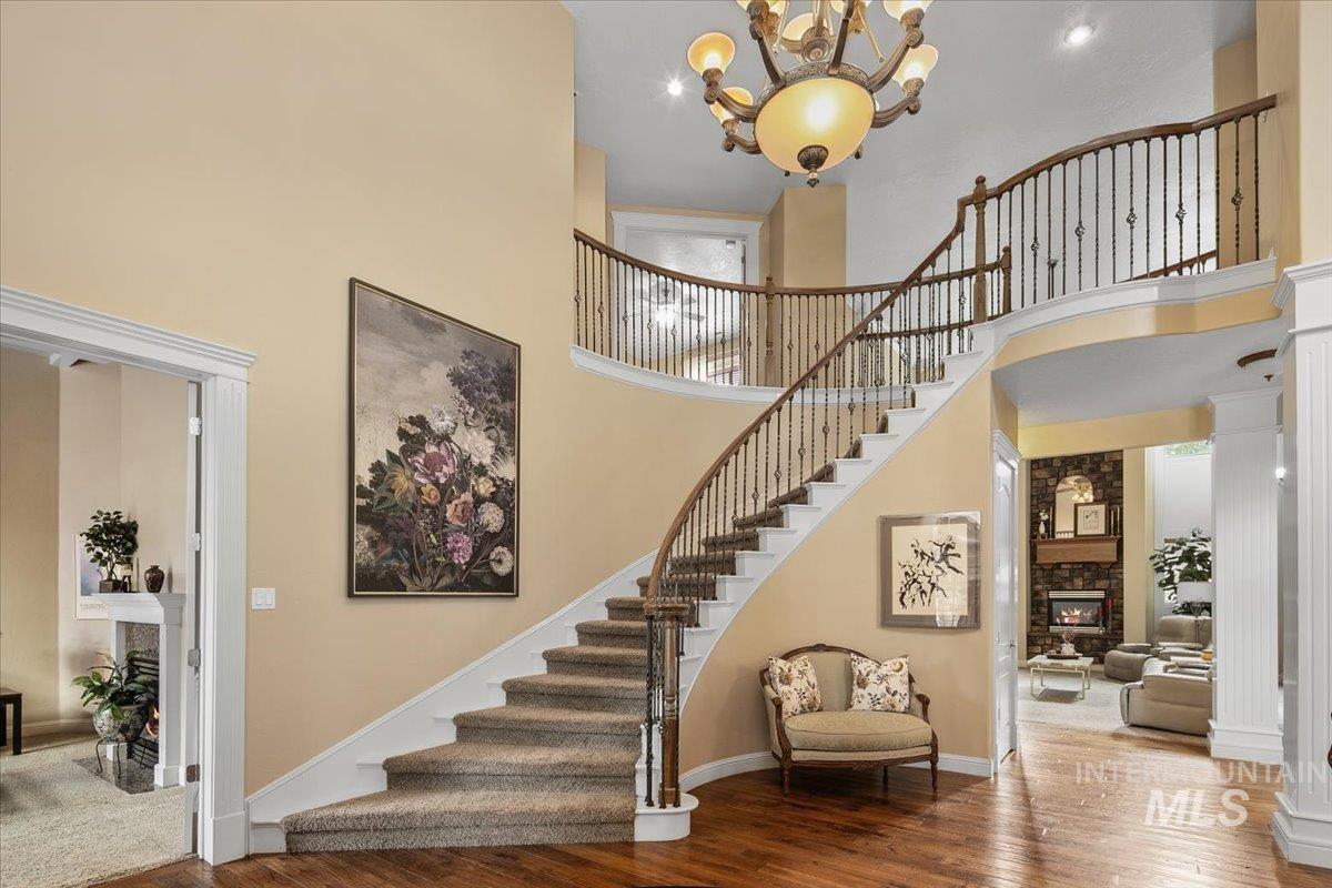 Staircase with a fireplace, a towering ceiling, hardwood / wood-style flooring, and a chandelier