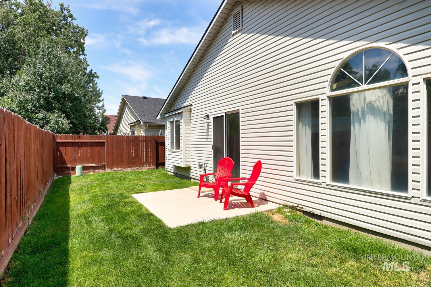 Expansive backyard featuring a concrete patio, verdant lawn, and a privacy fence