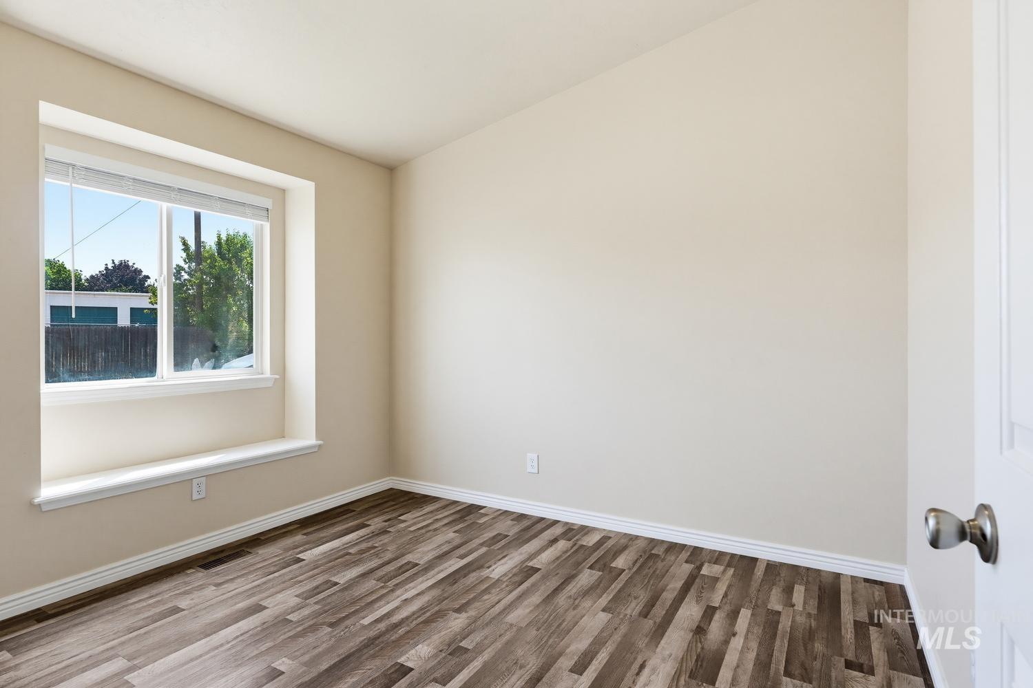 Room featuring neutral-toned walls, wood-finish flooring, and white baseboards