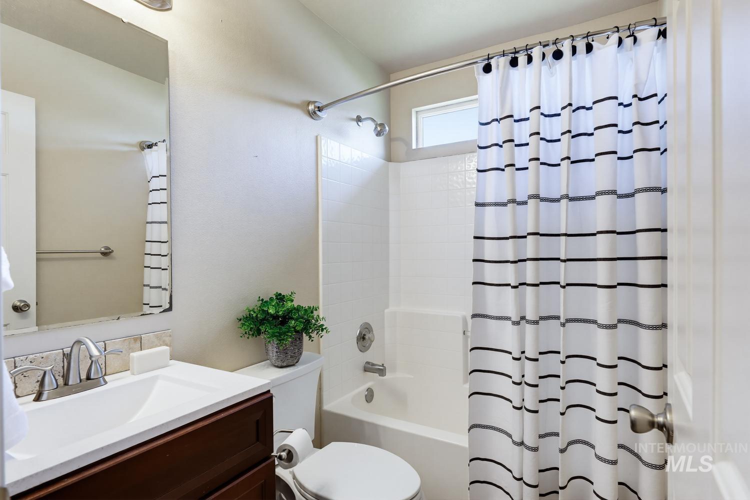 Full bathroom featuring a dark wood-finish vanity with an integrated sink, a tiled backsplash, and a shower-over-tub combination with white subway tile surround