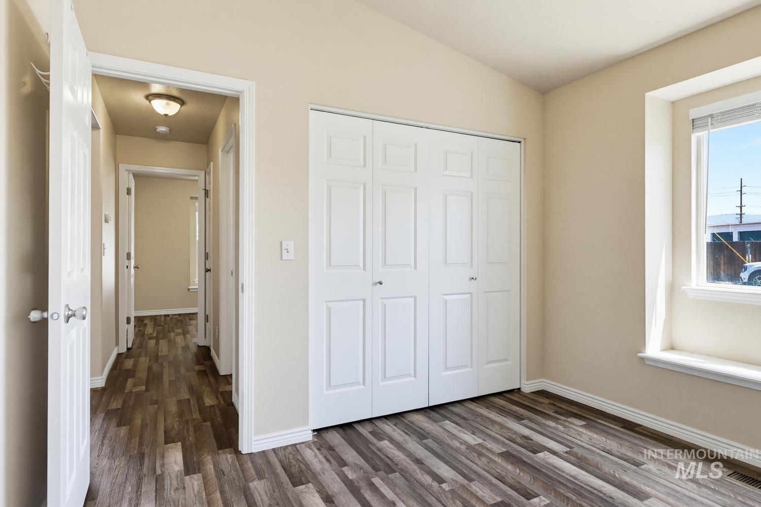 Spacious room featuring wood-finish flooring, a double bi-fold closet, and neutral wall tones