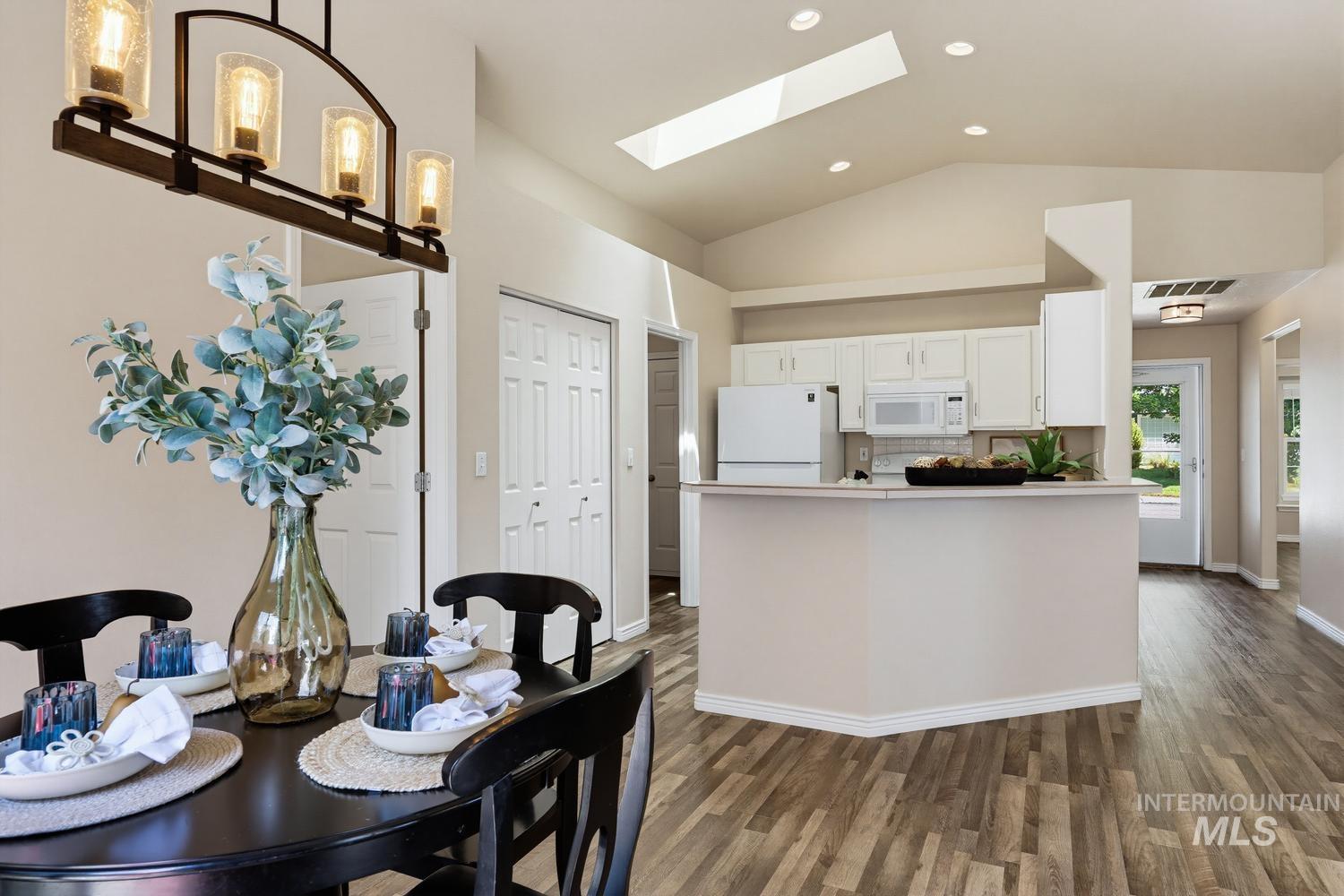 Open-concept living space featuring vaulted ceilings, a skylight, and wood-finish flooring