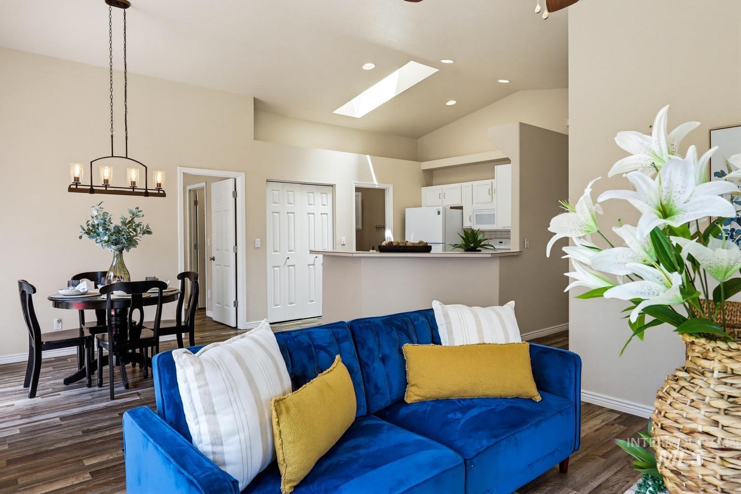 Vaulted ceiling with a skylight, wood-finish flooring, and a kitchen pass-through with a breakfast bar