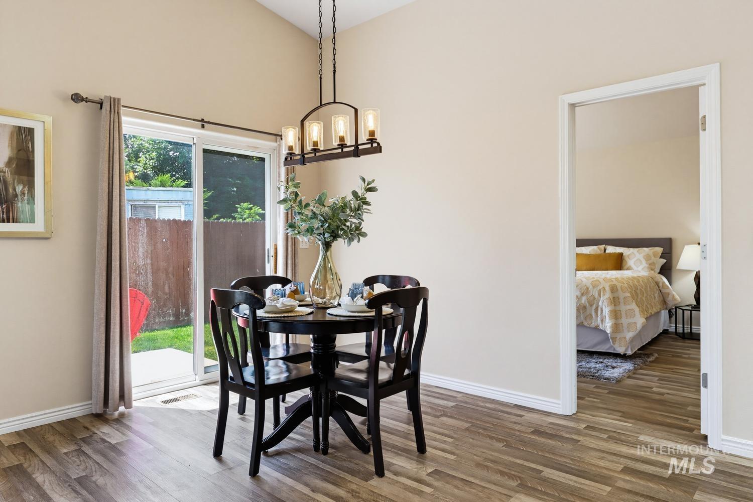 Dining area featuring vaulted ceilings, wood-finish flooring, and a modern linear chandelier