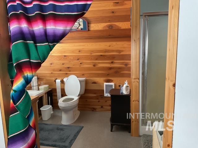 Bathroom with a stall shower, wooden walls, and vanity