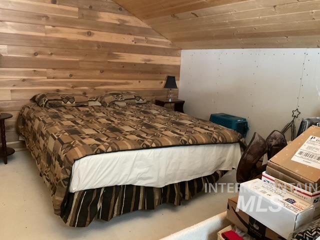 Bedroom with lofted ceiling, wood walls, and wooden ceiling