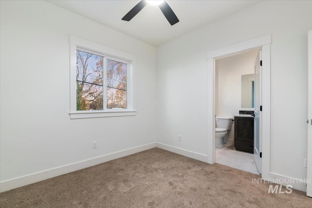 Unfurnished bedroom featuring light carpet, ceiling fan, and connected bathroom