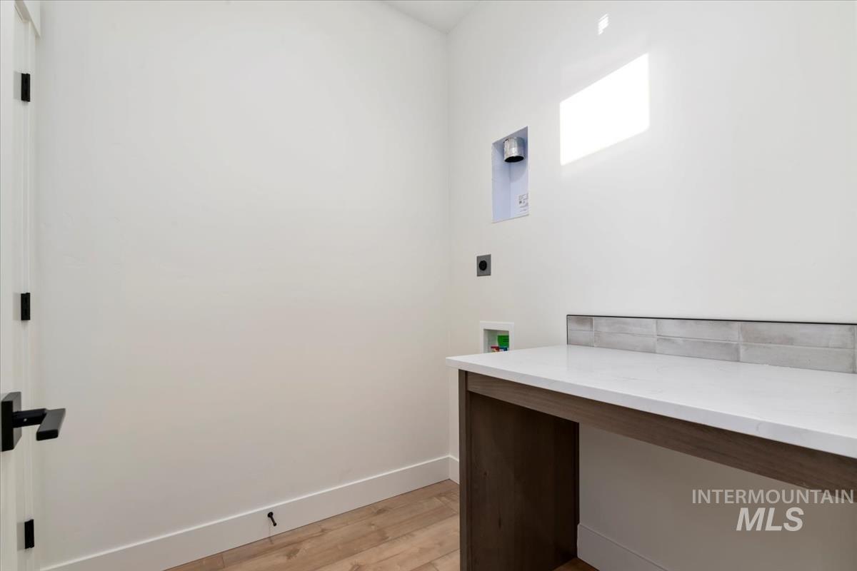Washroom with light wood-style flooring, washer hookup, and hookup for an electric dryer