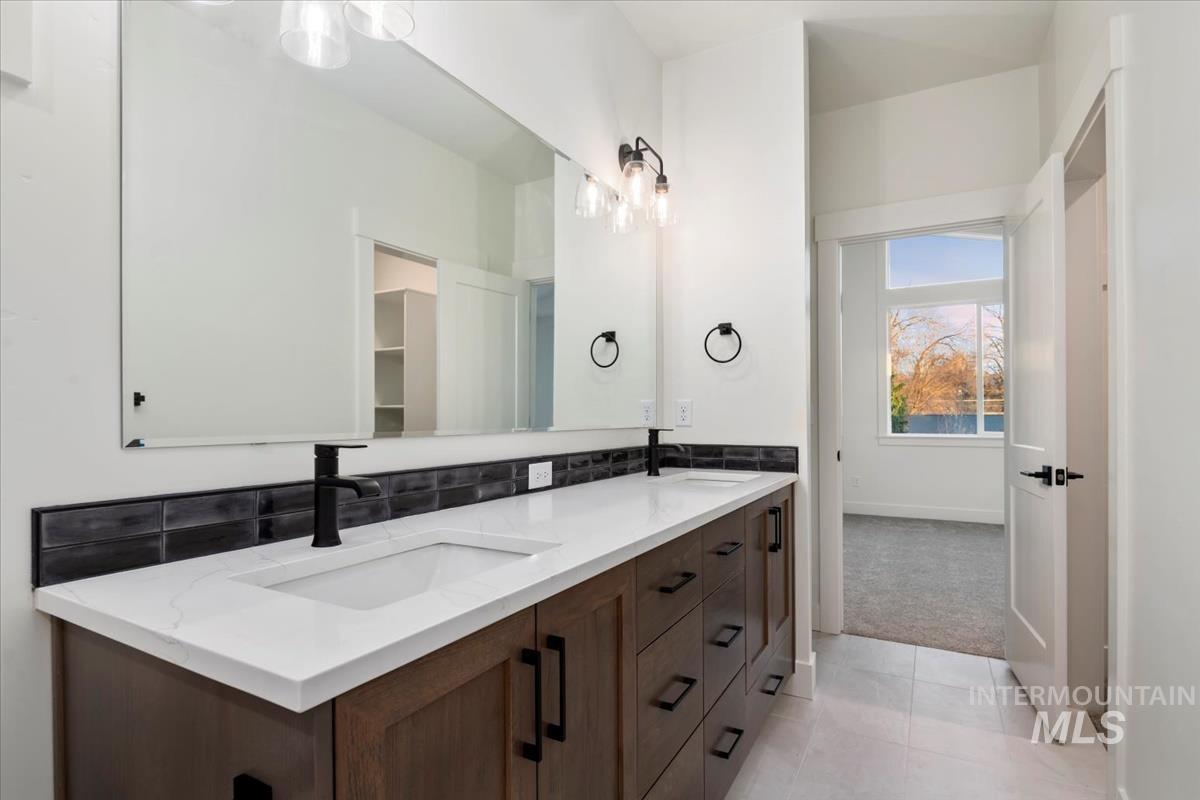 Bathroom with double vanity, backsplash, light carpet, and light tile patterned flooring
