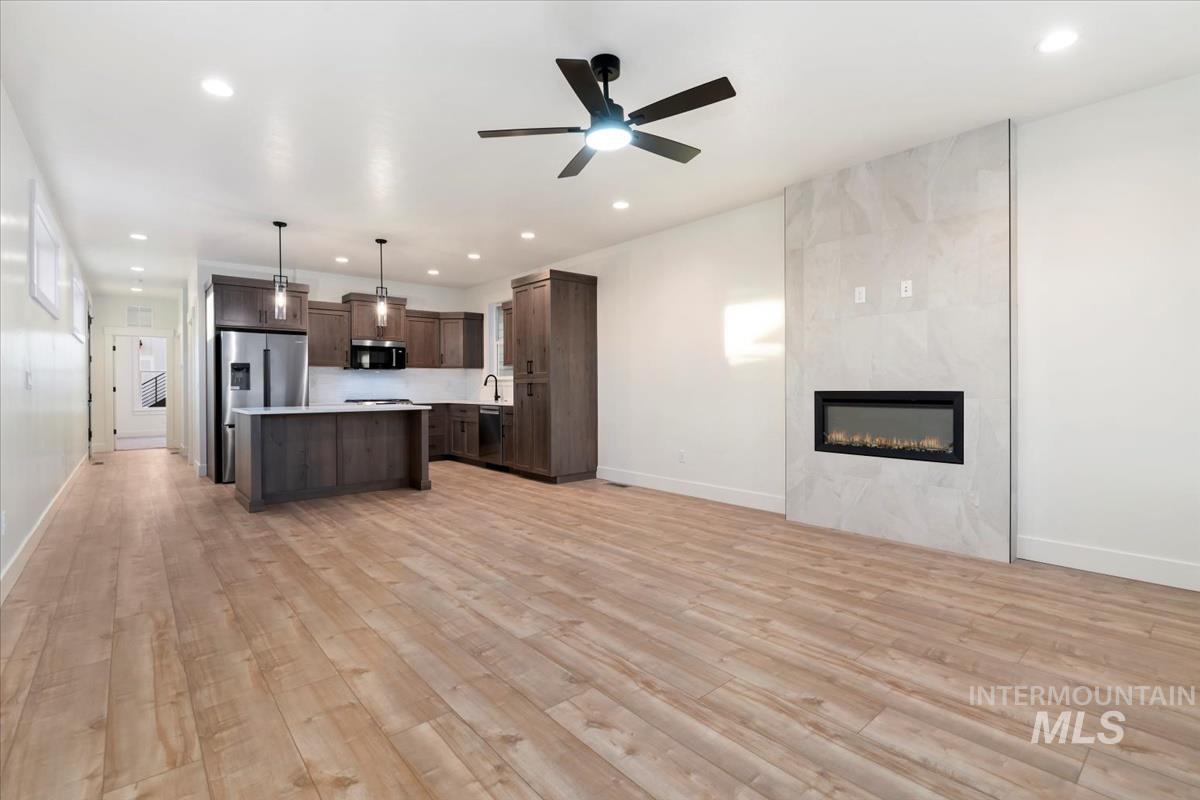 Kitchen with open floor plan, light countertops, pendant lighting, dark brown cabinetry, and recessed lighting