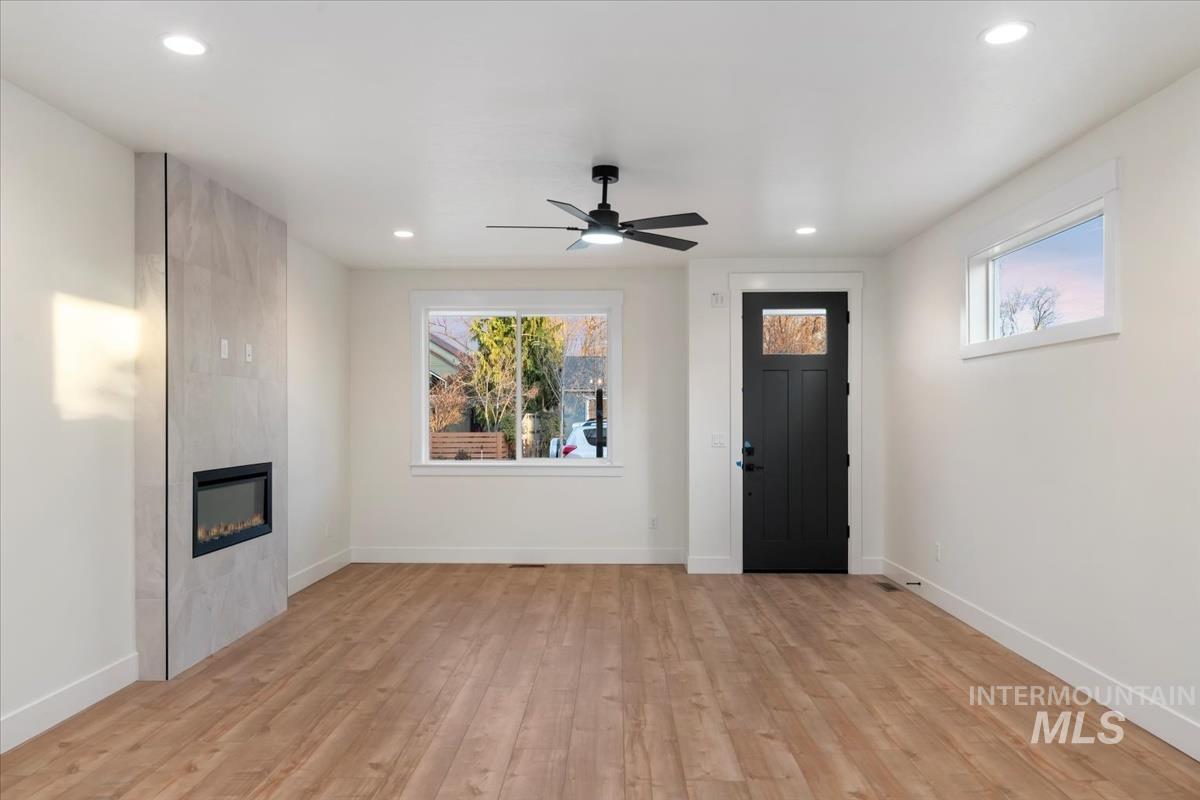 Unfurnished living room with plenty of natural light, light wood-style floors, a ceiling fan, a fireplace, and recessed lighting