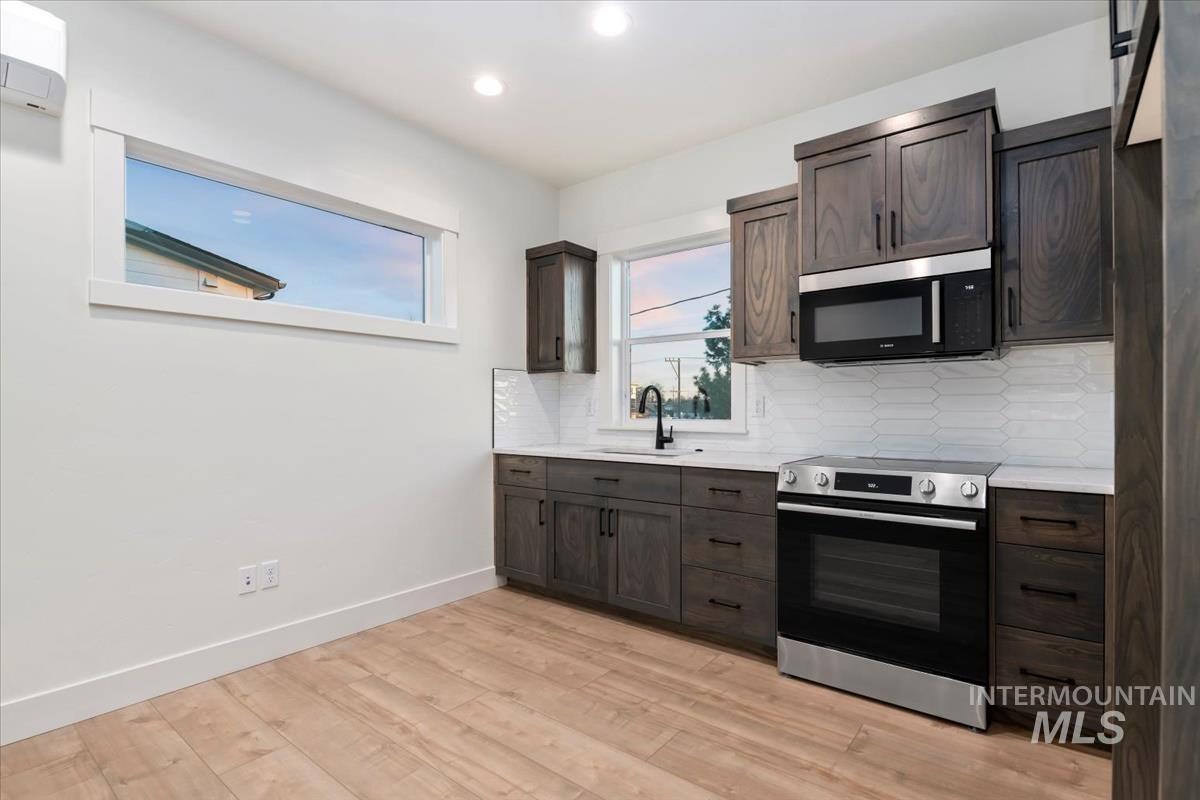 Kitchen featuring appliances with stainless steel finishes, dark brown cabinets, backsplash, and recessed lighting