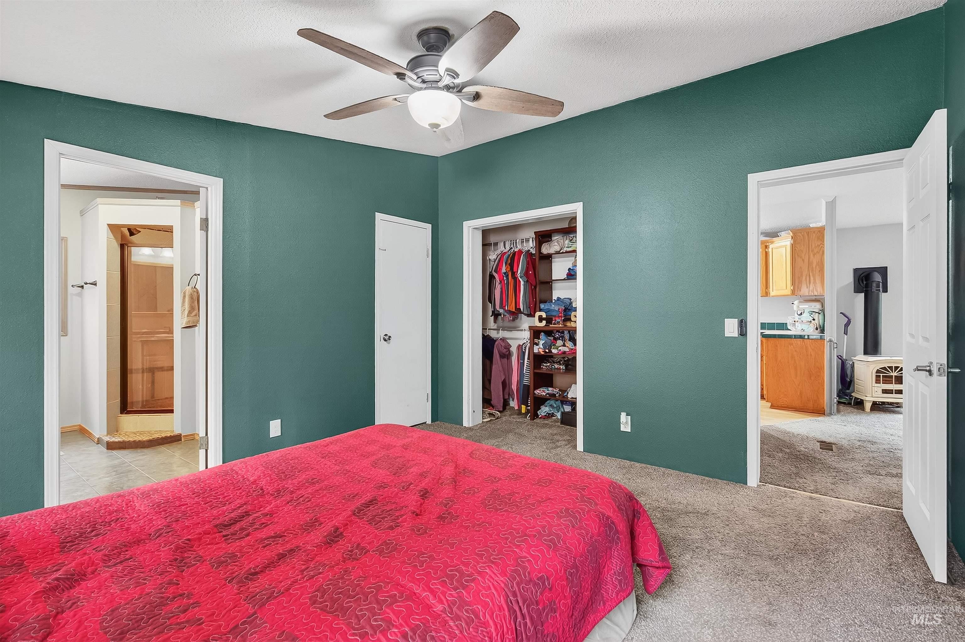 Bedroom featuring light carpet, ceiling fan, a closet, and ensuite bath