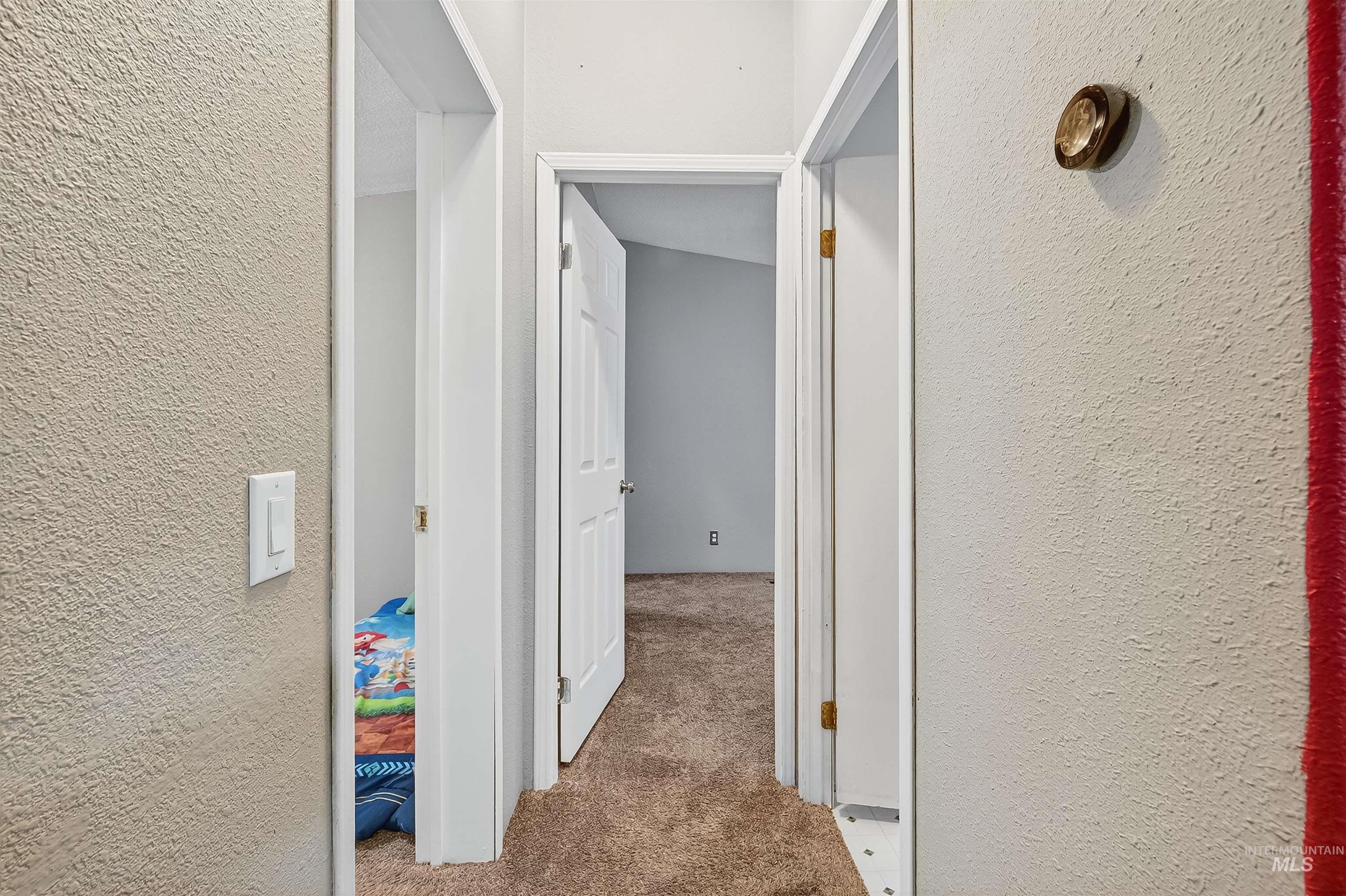 Hall featuring a textured wall and light carpet