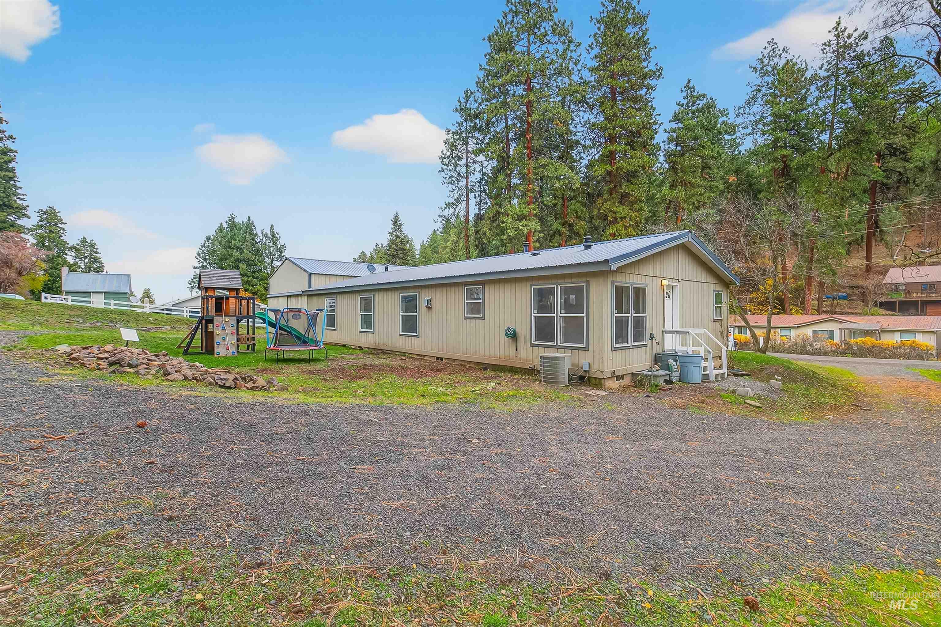 Back of property with a playground and a metal roof