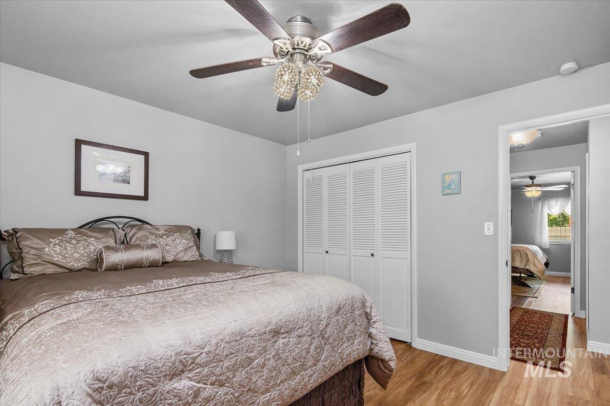 Bedroom with light wood-type flooring, a closet, and a ceiling fan