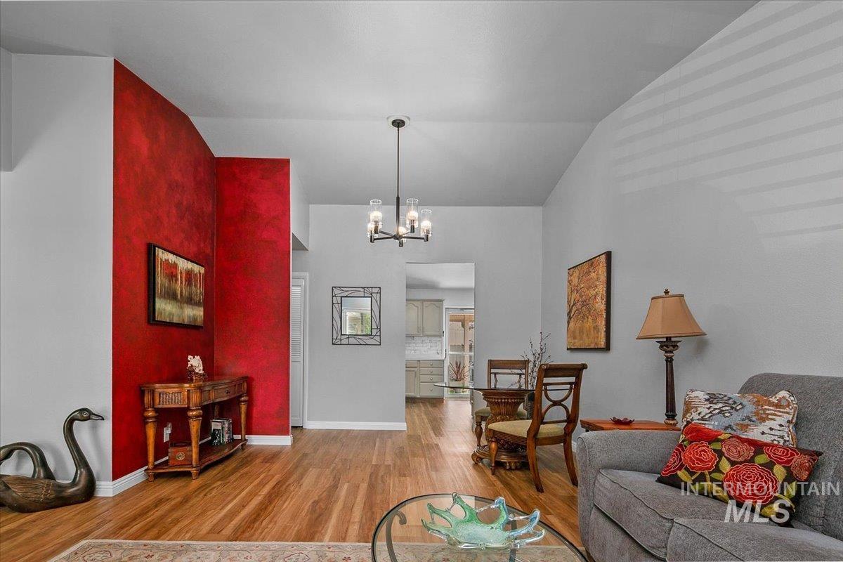 Living room featuring wood finished floors, a chandelier, and high vaulted ceiling