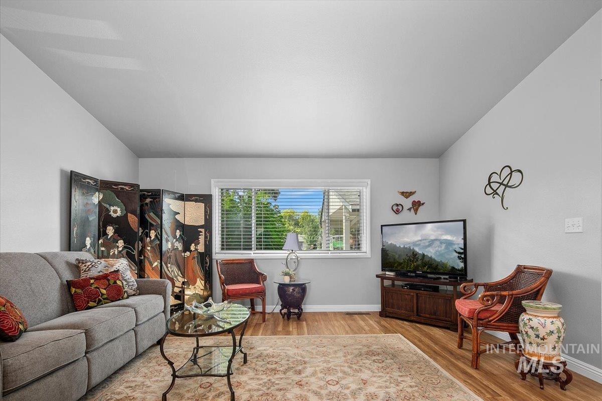 Living area with light wood-style floors and vaulted ceiling