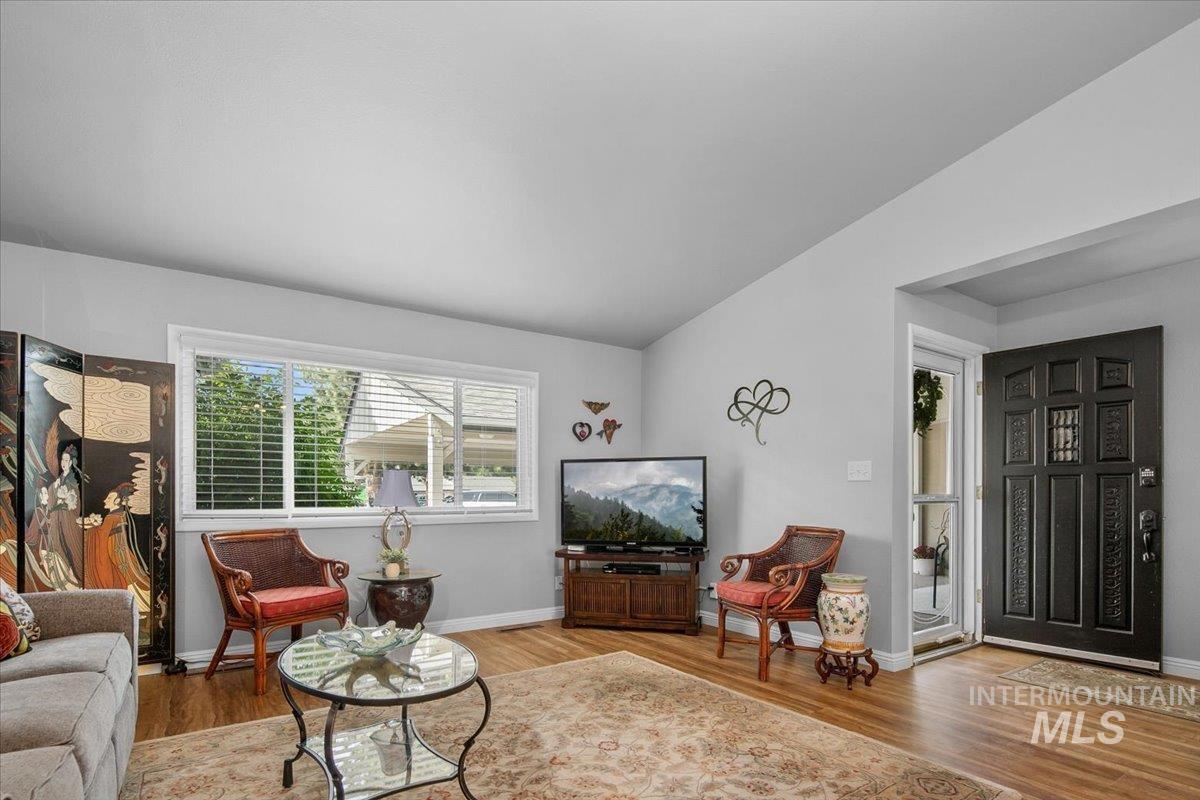 Living area with light wood finished floors and vaulted ceiling