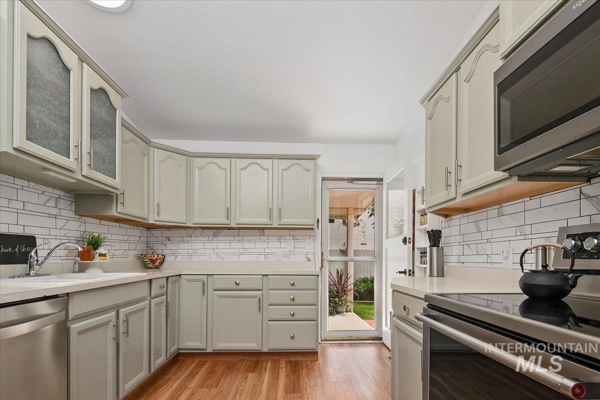 Kitchen featuring appliances with stainless steel finishes, decorative backsplash, and light wood-style floors