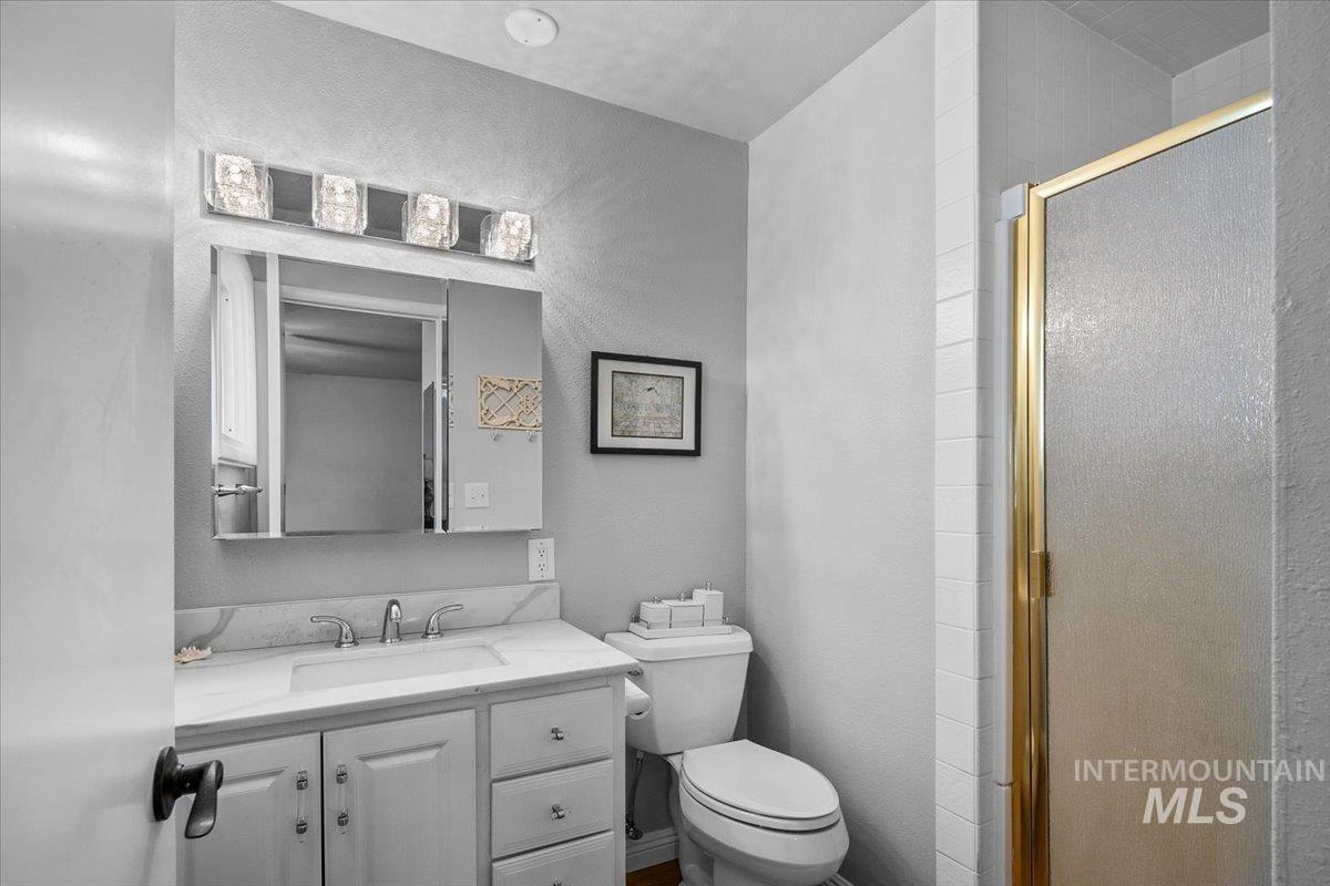Bathroom featuring a shower stall, vanity, and a textured wall
