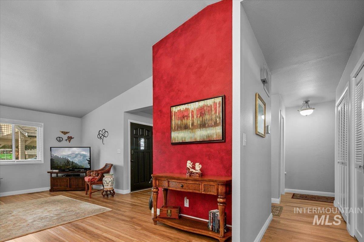 Foyer entrance with light wood finished floors and vaulted ceiling