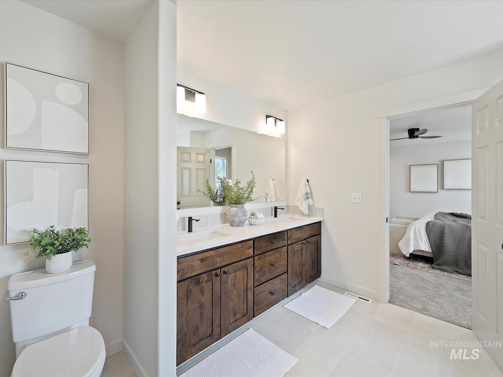Bathroom featuring ensuite bathroom, double vanity, a ceiling fan, and light tile patterned floors