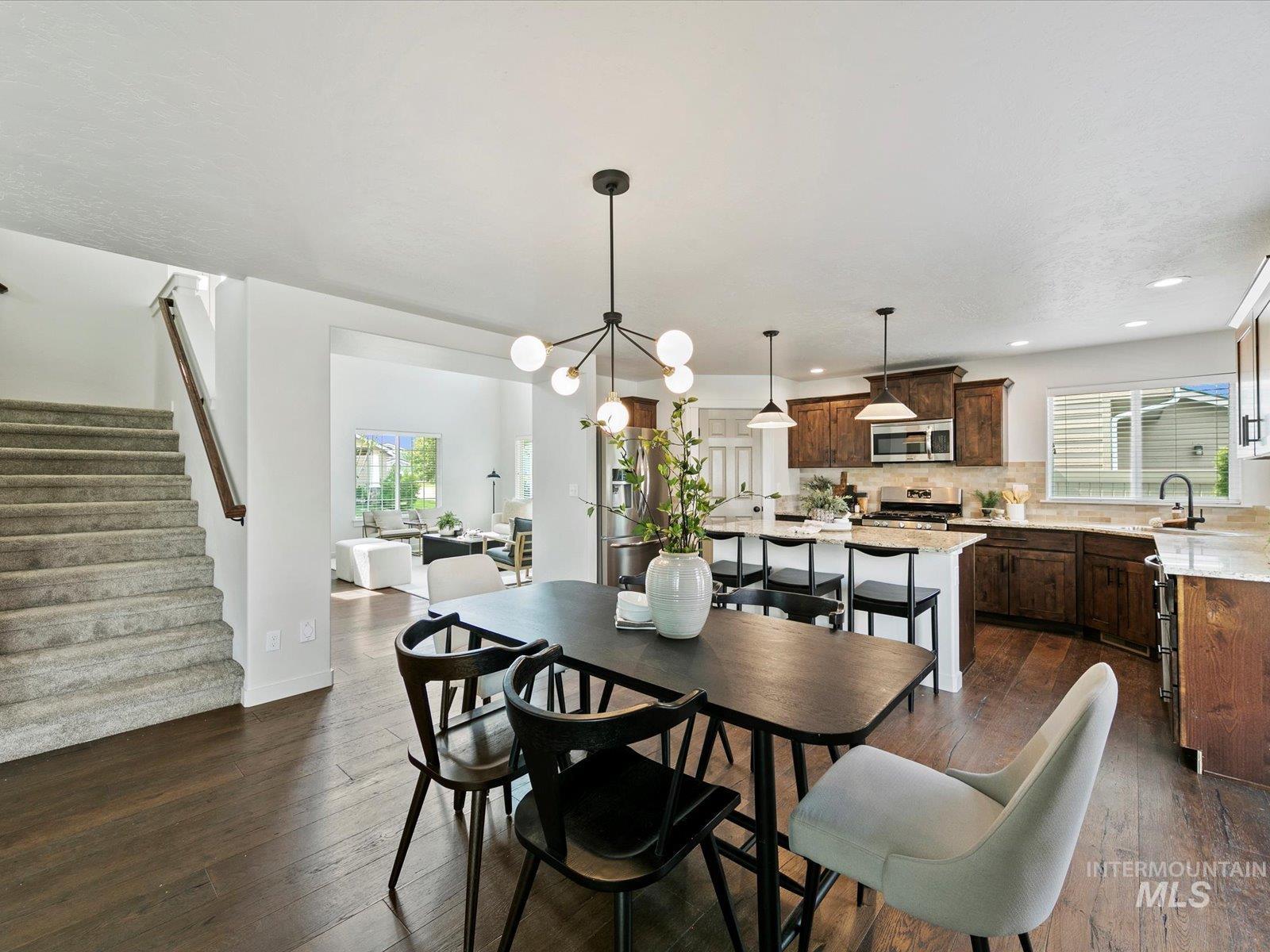 Dining space with a chandelier, healthy amount of natural light, stairs, dark wood-style floors, and recessed lighting