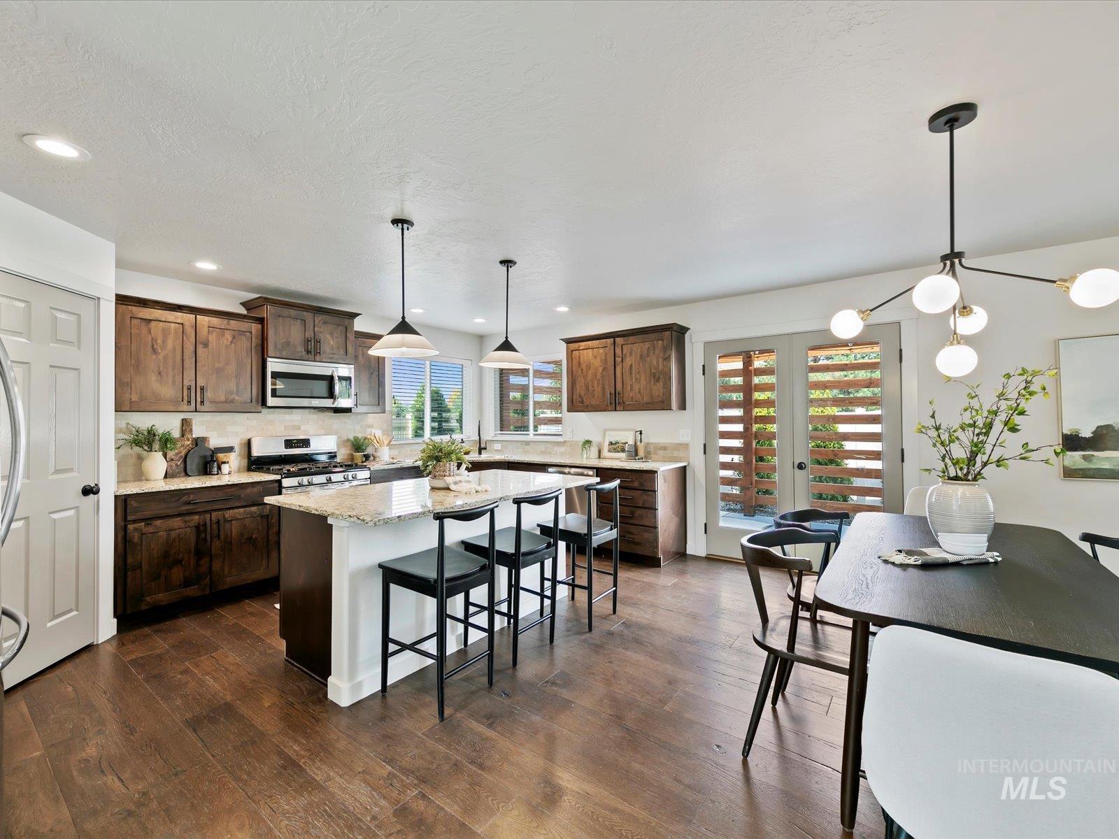 Kitchen featuring pendant lighting, a breakfast bar area, light stone countertops, a kitchen island, and dark brown cabinetry