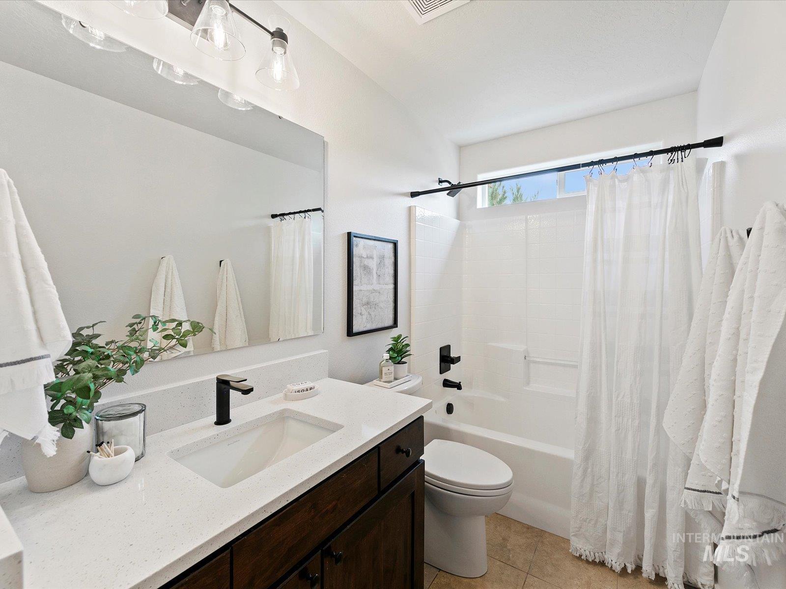 Bathroom featuring shower / bathtub combination with curtain, vanity, and light tile patterned flooring