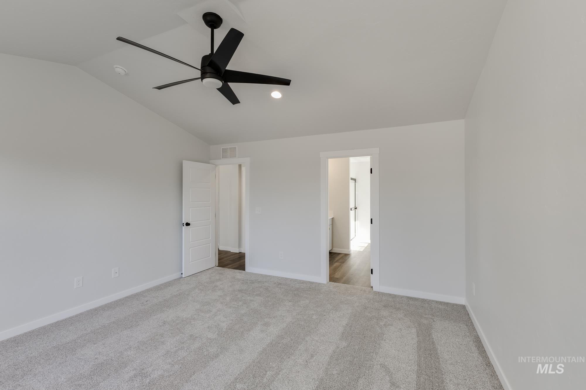 Unfurnished bedroom featuring a ceiling fan, lofted ceiling, carpet floors, and ensuite bathroom