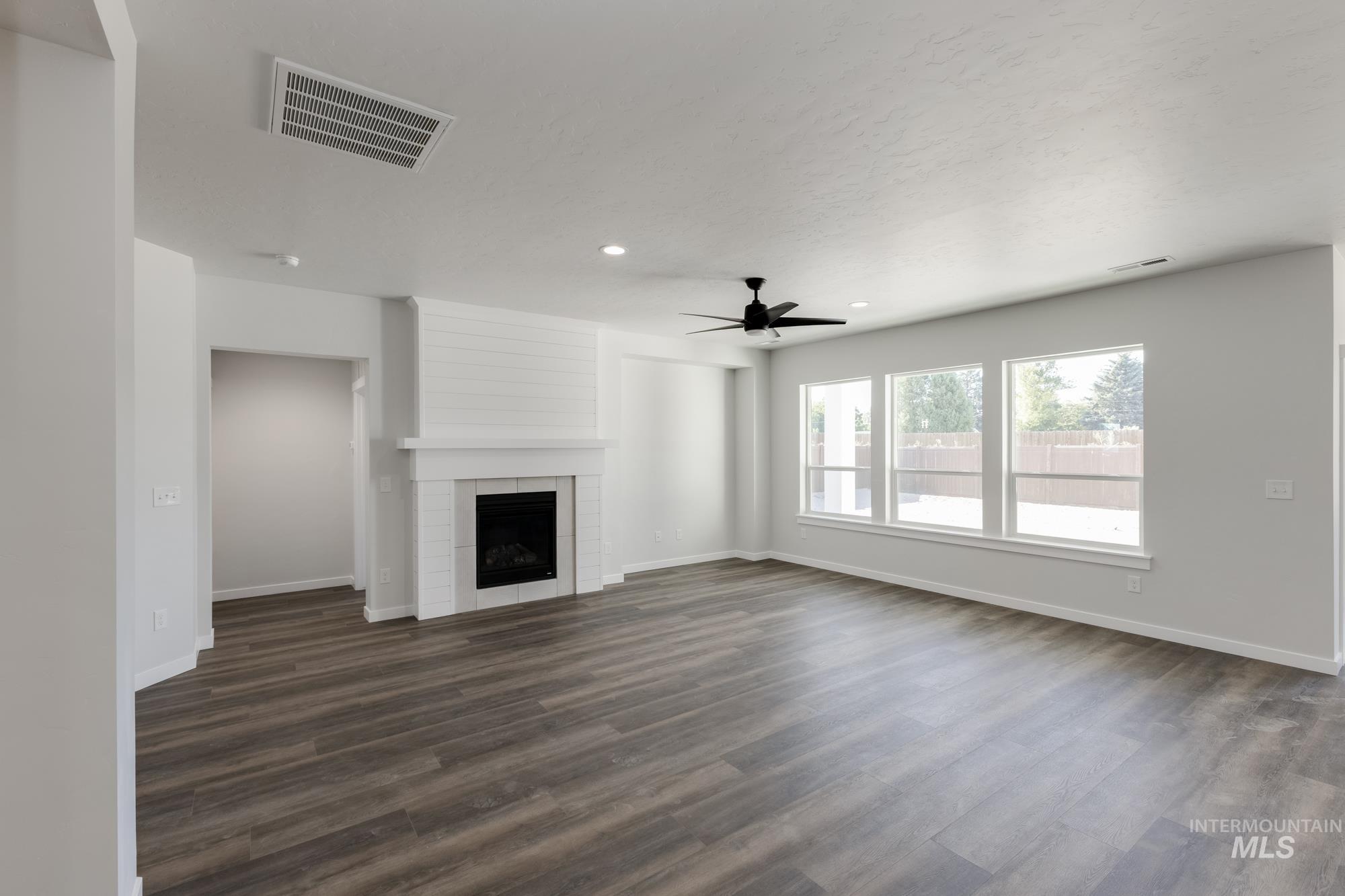Unfurnished living room with a fireplace, dark wood finished floors, ceiling fan, and recessed lighting