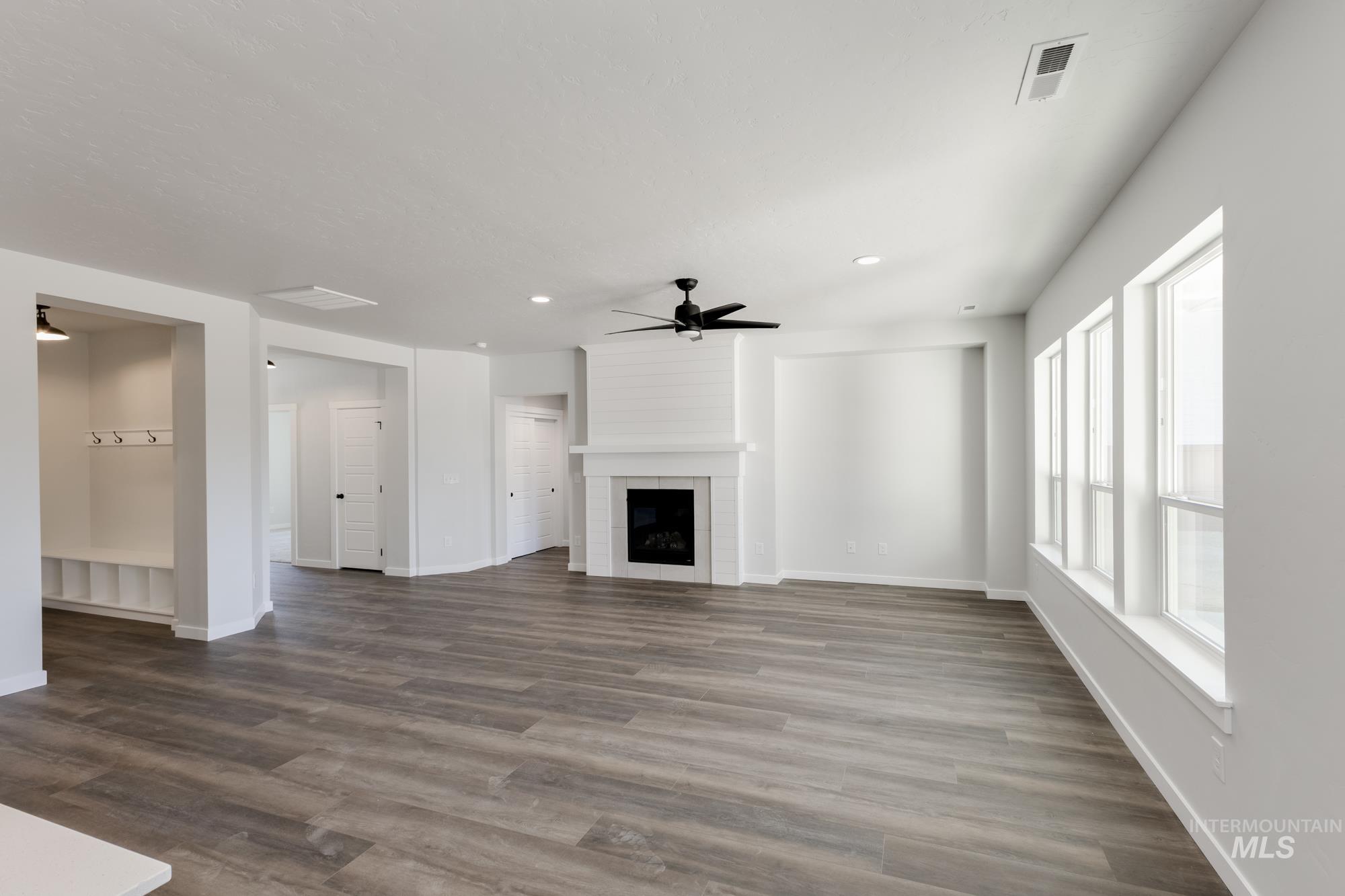 Unfurnished living room with wood finished floors, a large fireplace, a ceiling fan, and recessed lighting
