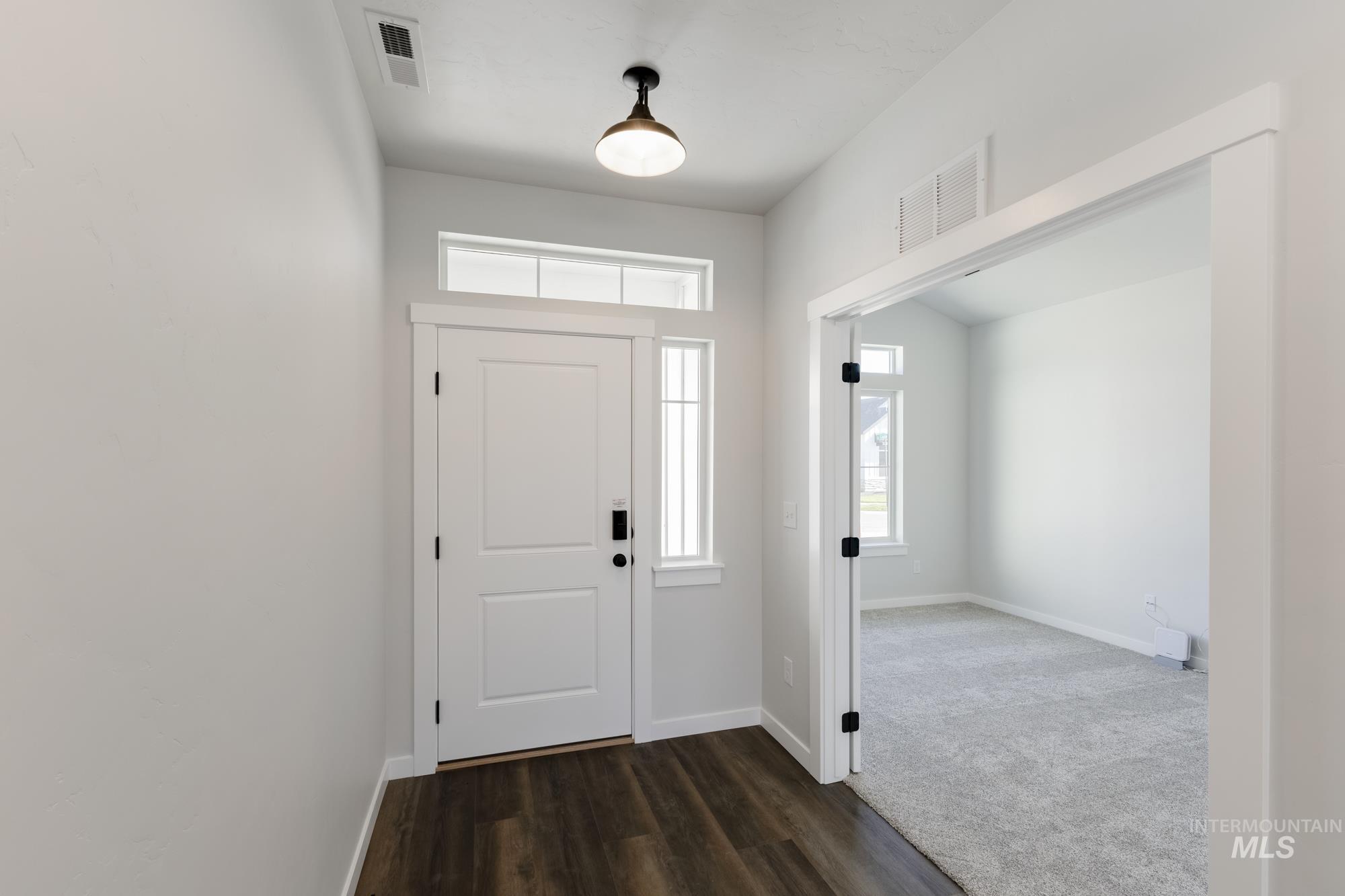 Entrance foyer featuring dark wood-style floors and dark carpet