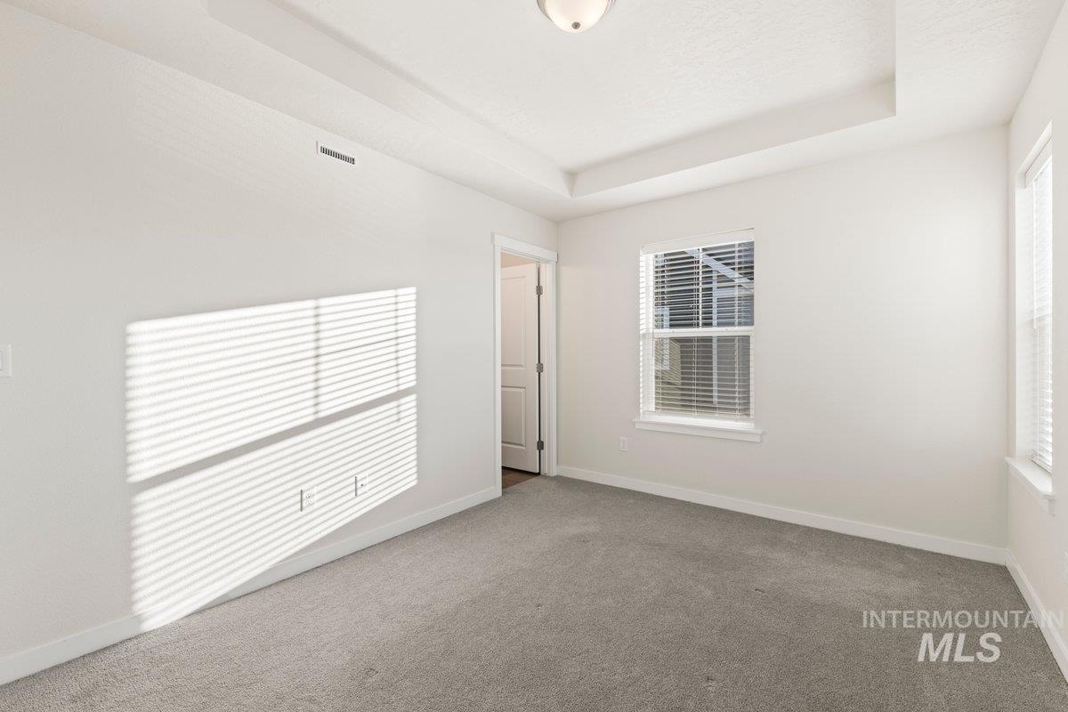 Carpeted empty room featuring a raised ceiling