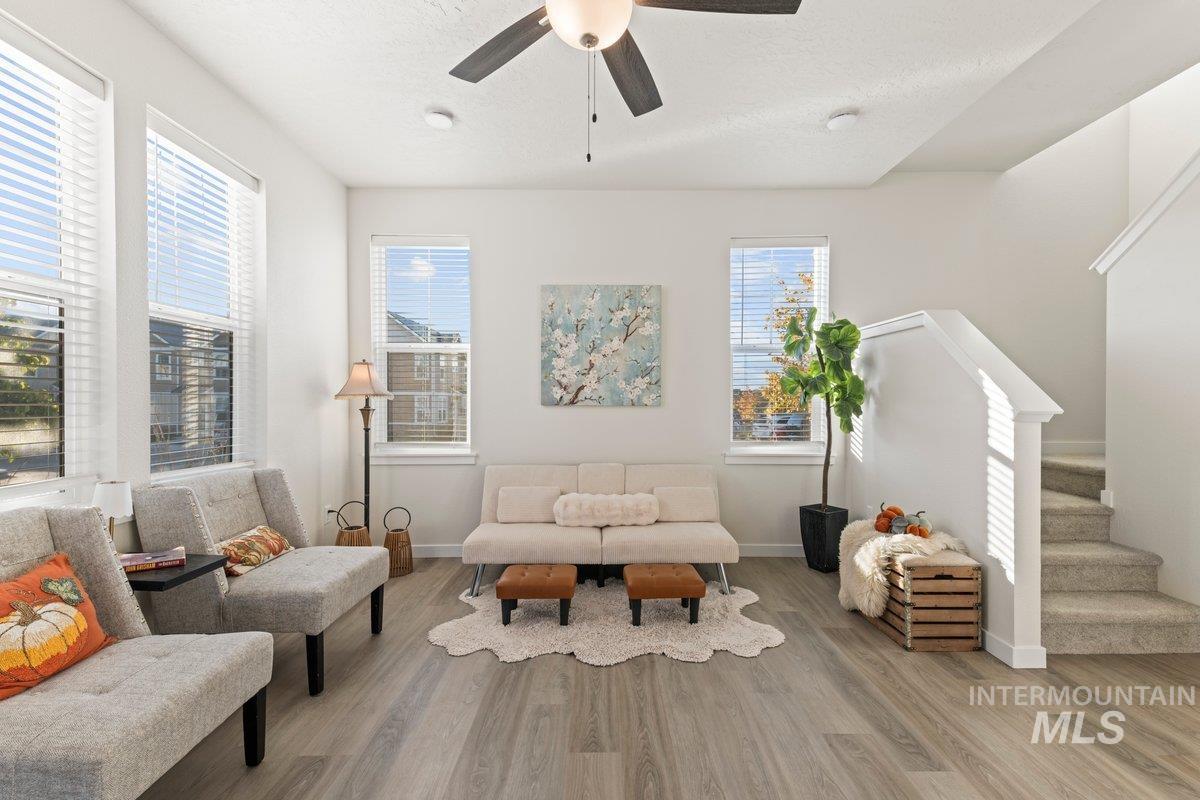 Living area with wood finished floors, stairway, a ceiling fan, and a textured ceiling