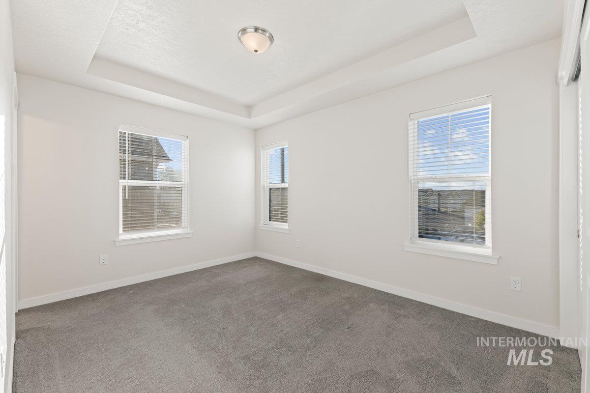 Empty room with a raised ceiling and carpet floors