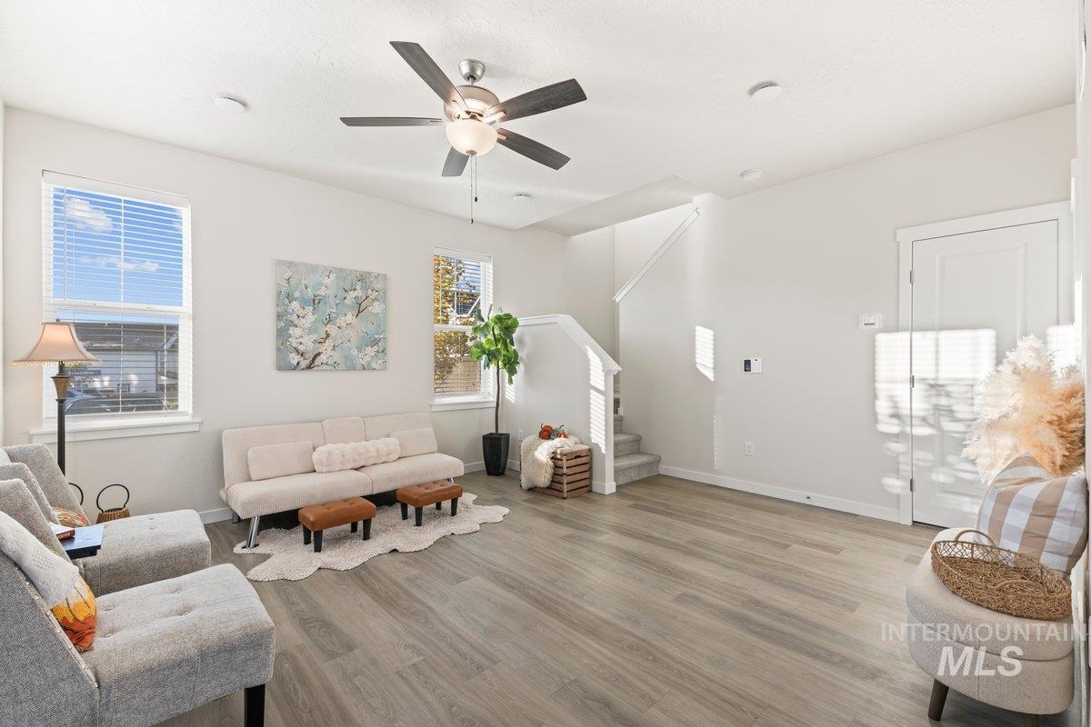 Living area featuring stairs, light wood-type flooring, and a ceiling fan