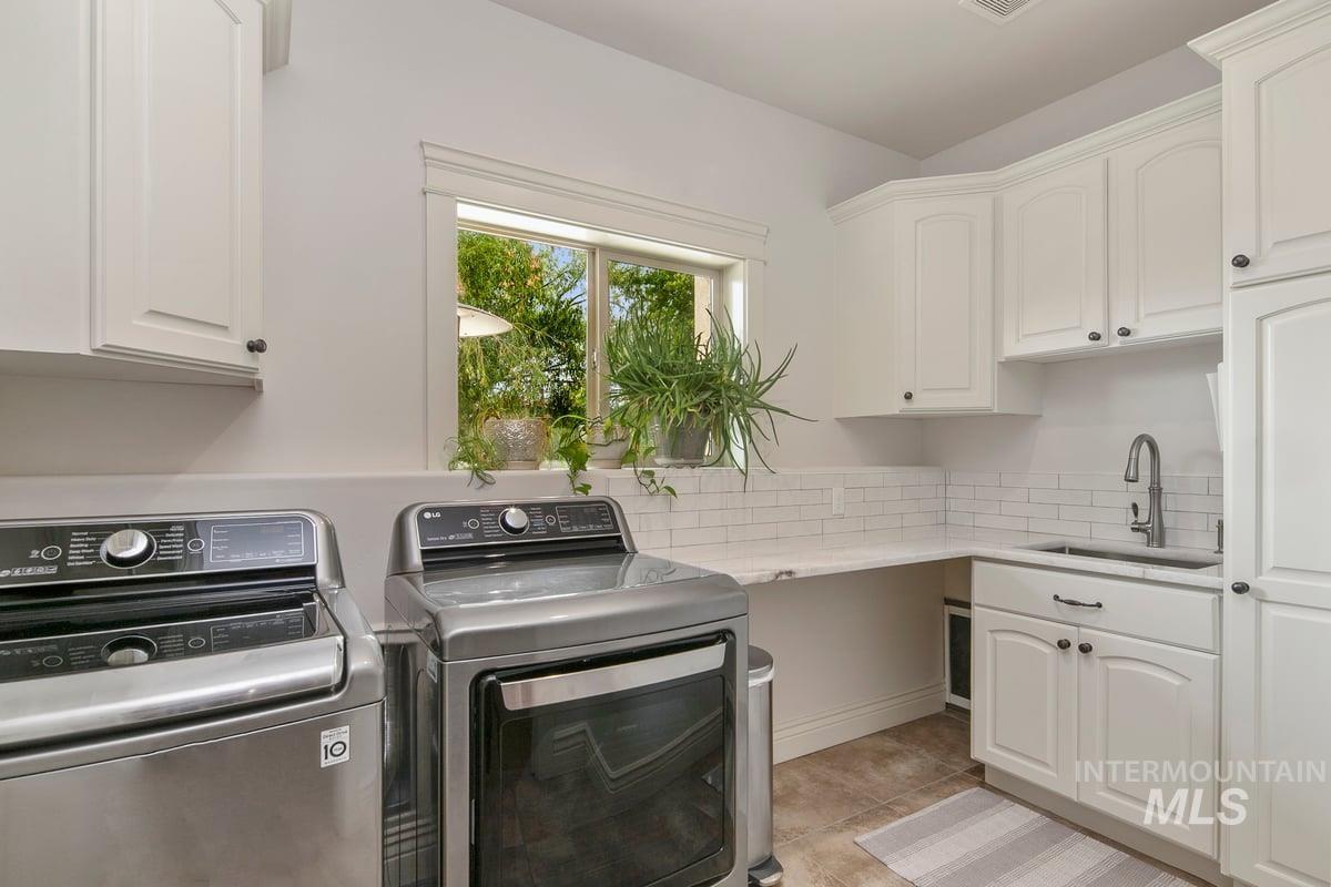 Laundry area featuring cabinet space, washer and clothes dryer, and light tile patterned flooring