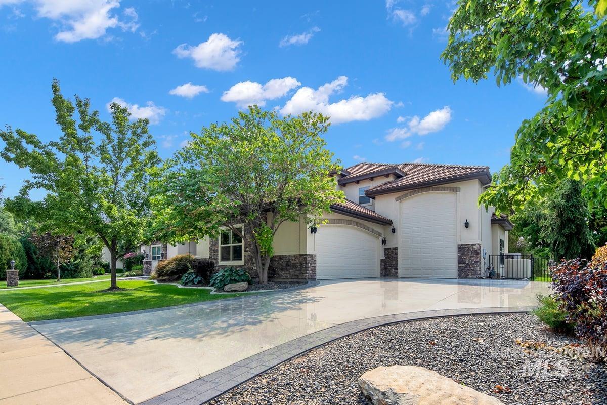 View of front of home with a garage, driveway, stucco siding, stone siding, and a front yard