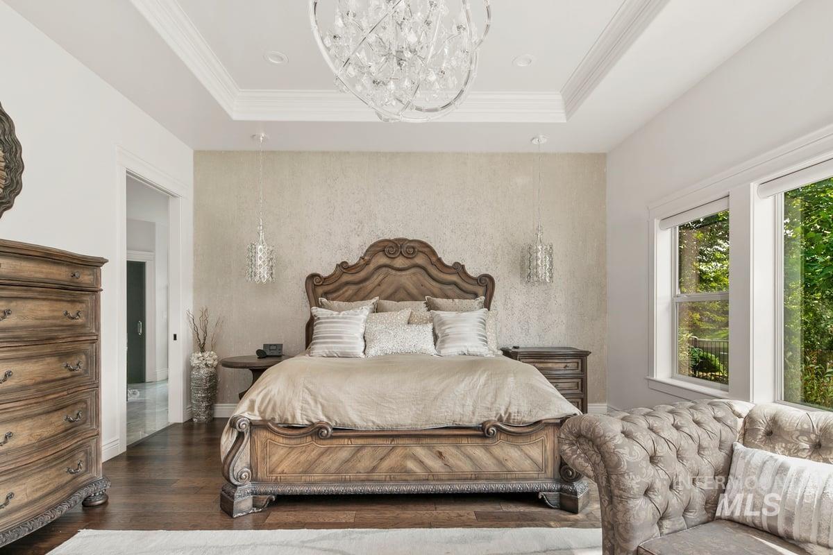 Bedroom featuring wood finished floors, a chandelier, crown molding, and a tray ceiling