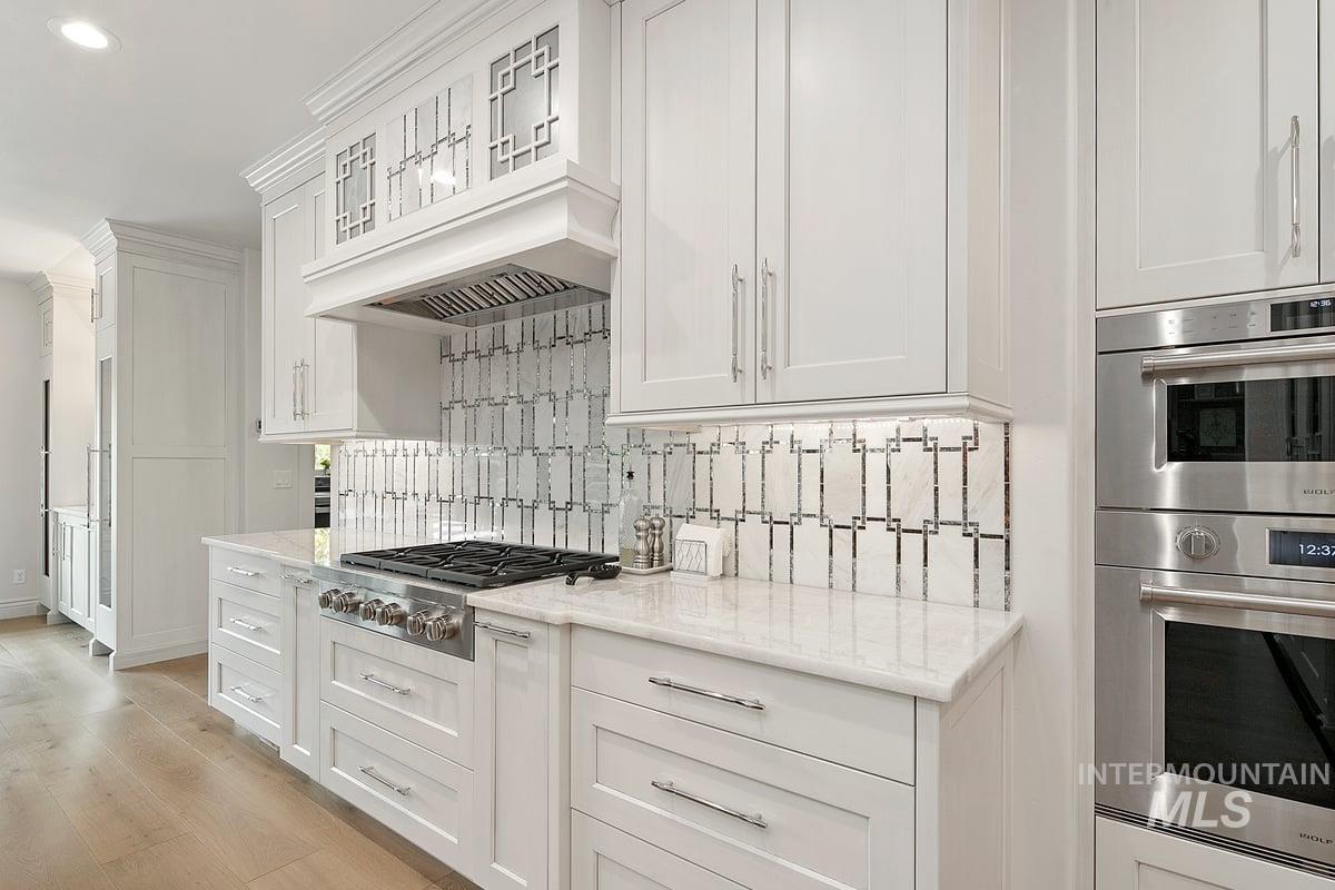 Kitchen with appliances with stainless steel finishes, white cabinetry, light stone countertops, decorative backsplash, and recessed lighting