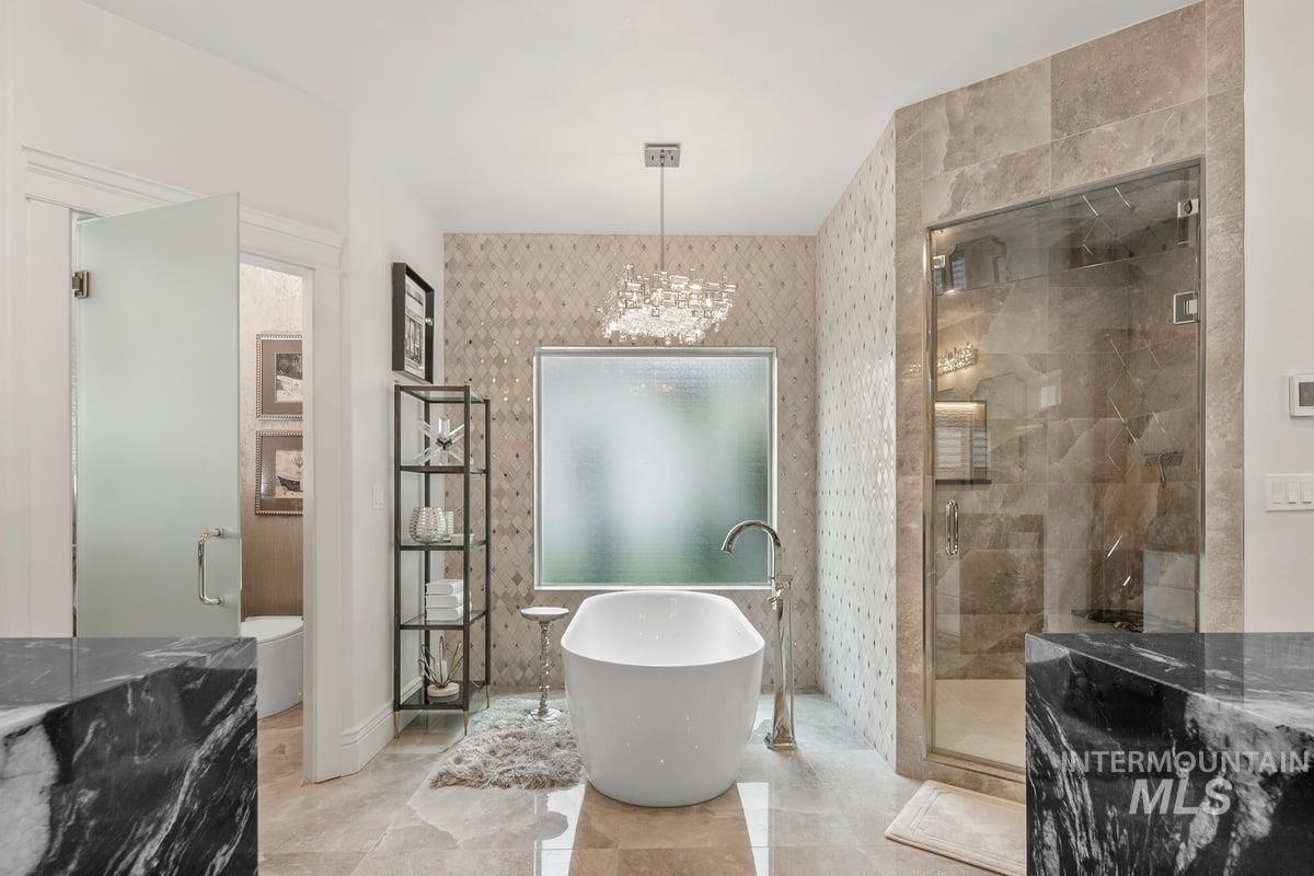 Bathroom with a soaking tub, a shower stall, and a chandelier