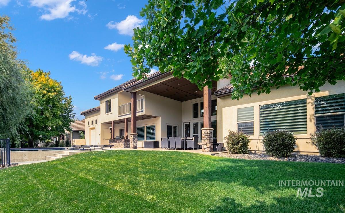 Rear view of house with a patio area, stucco siding, and a lawn