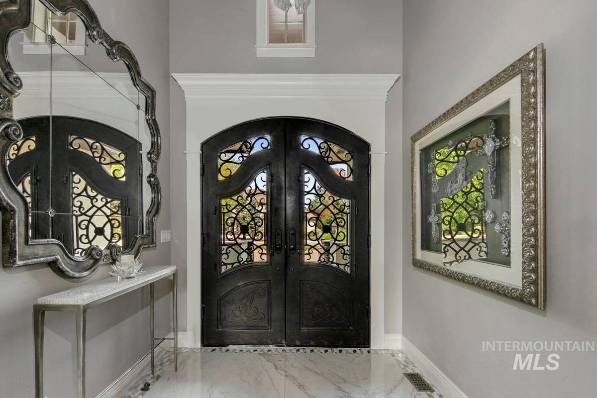 Foyer entrance featuring french doors, marble finish flooring, and ornamental molding