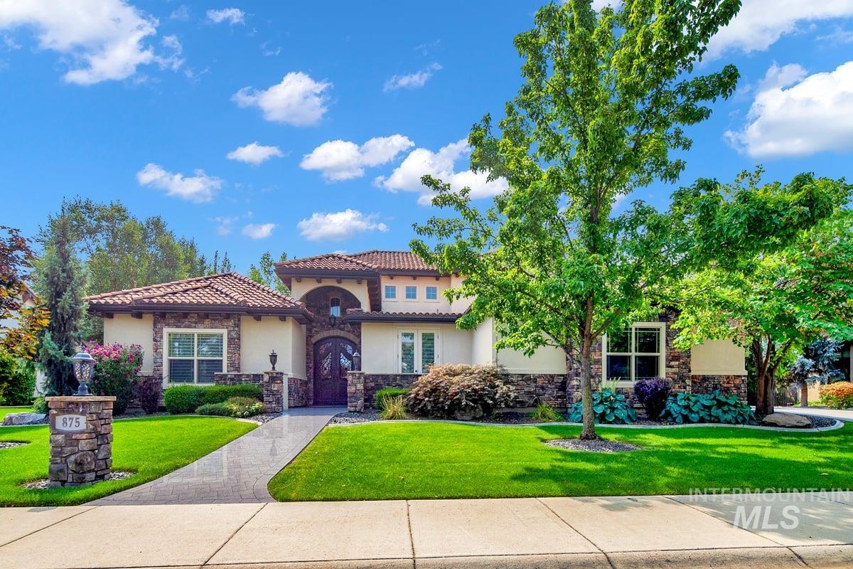 Mediterranean / spanish-style house featuring stone siding, a front lawn, stucco siding, and a tile roof